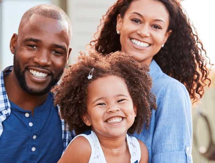 Family - father, mother and child - smiling at camera