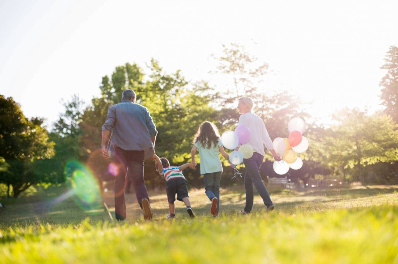 Family holding hands and walking through field