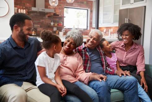 Family sitting on couch smiles and looks at each other
